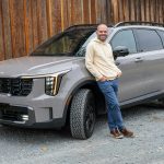 A man standing next to a gray suv