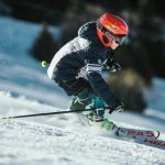 A skier in motion wearing winter gear, gliding swiftly down a snowy slope.